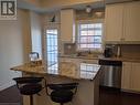 Kitchen with a breakfast bar, backsplash, sink, stainless steel dishwasher, and dark hardwood / wood-style floors - 9 Hyde Park Mews, Kitchener, ON  - Indoor Photo Showing Kitchen 