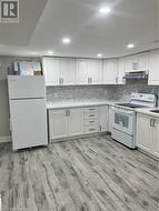 Kitchen featuring backsplash, white cabinetry, white appliances, and light wood-type flooring - 