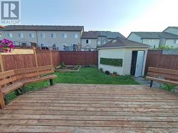 Wooden terrace featuring a lawn and a storage shed - 