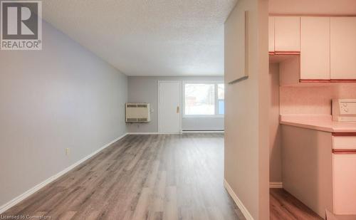 Unfurnished living room featuring heating unit, light hardwood / wood-style floors, a textured ceiling, and a baseboard heating unit - 1200 Courtland Avenue E Unit# 27, Kitchener, ON - Indoor Photo Showing Other Room