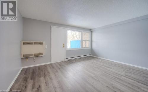 Spare room featuring heating unit, light wood-type flooring, a textured ceiling, and a baseboard heating unit - 1200 Courtland Avenue E Unit# 27, Kitchener, ON - Indoor Photo Showing Other Room