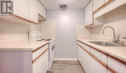 Kitchen featuring white cabinetry, sink, light hardwood / wood-style flooring, white range with electric cooktop, and decorative backsplash - 1200 Courtland Avenue E Unit# 27, Kitchener, ON - Indoor Photo Showing Kitchen