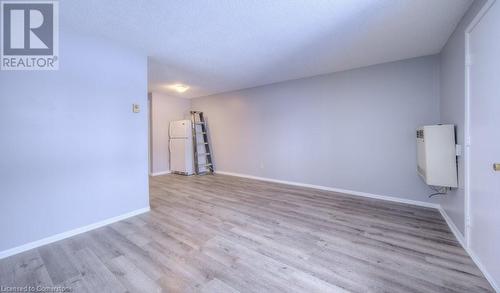 Spare room featuring light wood-type flooring, a textured ceiling, and heating unit - 1200 Courtland Avenue E Unit# 27, Kitchener, ON - Indoor Photo Showing Other Room