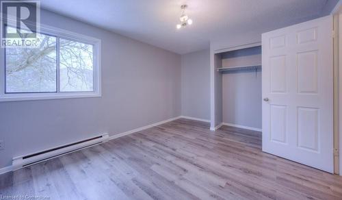 Unfurnished bedroom with a closet, an inviting chandelier, light hardwood / wood-style flooring, and a baseboard radiator - 1200 Courtland Avenue E Unit# 27, Kitchener, ON - Indoor Photo Showing Other Room