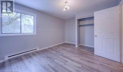 Unfurnished bedroom with a closet, an inviting chandelier, light hardwood / wood-style flooring, and a baseboard radiator - 