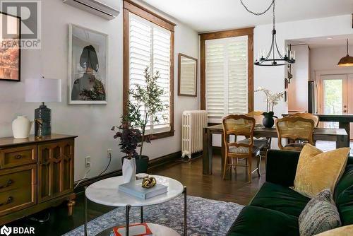 Living room featuring radiator heating unit, a wall unit AC, a notable chandelier, and dark hardwood floors - 109 Fairleigh Avenue S, Hamilton, ON - Indoor Photo Showing Living Room