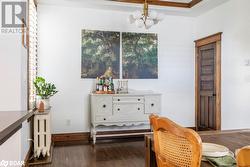 Living area with crown molding, radiator heating unit, dark hardwood flooring, and a notable chandelier - 