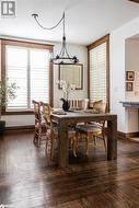 Dining area featuring dark hardwood flooring and a notable chandelier - 