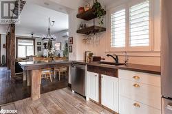 Kitchen featuring a wall mounted AC, sink, stainless steel dishwasher, white cabinetry, and light flooring - 