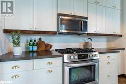 Kitchen with white cabinetry, appliances with stainless steel finishes, and light floors - 