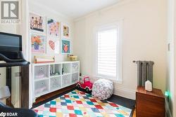 Game room with dark wood flooring, radiator heating unit, and crown molding - 