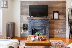 Family room featuring radiator, wood walls, fireplace, and hardwood flooring - 