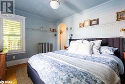 Bedroom featuring radiator, hardwood flooring, and ornamental molding - 