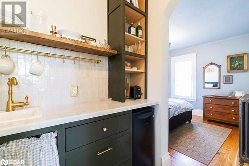 Bar featuring hardwood floors, sink, tasteful backsplash, crown molding, and black refrigerator - 109 Fairleigh Avenue S, Hamilton, ON - Indoor Photo Showing Other Room