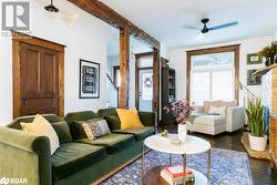 Living room with beamed ceiling, dark hardwood floors, and ceiling fan - 