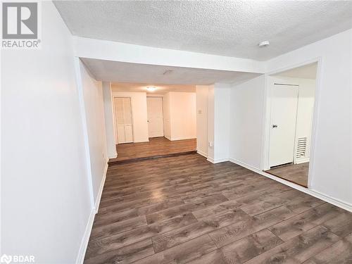 Spare room featuring a textured ceiling and dark wood-type flooring - 1306 Leighland Road Unit# Ll, Burlington, ON - Indoor Photo Showing Other Room