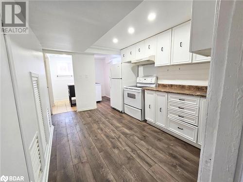 Kitchen featuring dark stone countertops, dark hardwood / wood-style flooring, white cabinets, and white appliances - 1306 Leighland Road Unit# Ll, Burlington, ON - Indoor Photo Showing Other Room