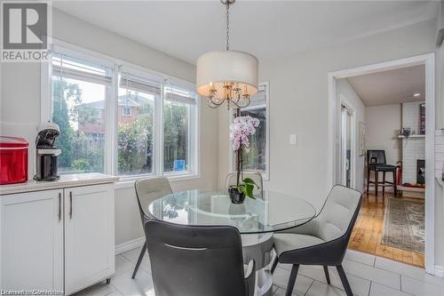 Dining area featuring a brick fireplace, a chandelier, and light wood-type flooring - 134 Bayne Crescent, Cambridge, ON 