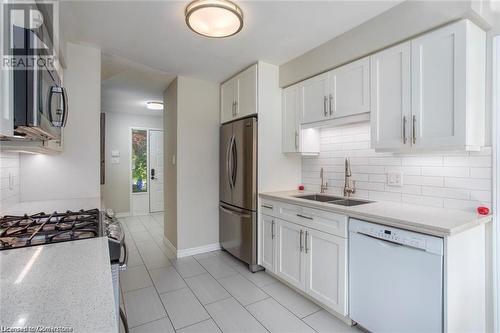 Kitchen with white cabinets, light stone counters, sink, and appliances with stainless steel finishes - 134 Bayne Crescent, Cambridge, ON 