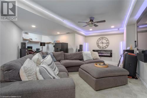 Living room featuring a tray ceiling, ceiling fan, and light colored carpet - 134 Bayne Crescent, Cambridge, ON 