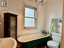 Bathroom featuring a tub to relax in, sink, a chandelier, and toilet - 