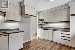 Kitchen with white cabinetry, sink, and light hardwood / wood-style flooring - 