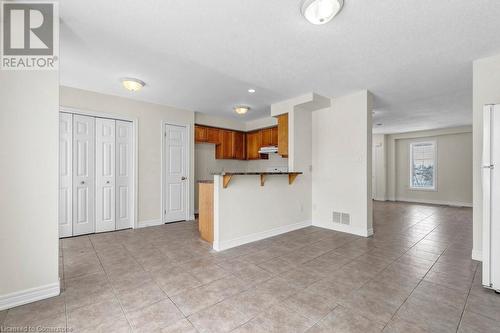 Kitchen featuring a breakfast bar, a textured ceiling, kitchen peninsula, and light tile patterned flooring - 529 Victoria Road N, Guelph, ON - Indoor Photo Showing Kitchen