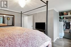 Bedroom featuring a closet, crown molding, hardwood / wood-style flooring, a textured ceiling, and a chandelier - 