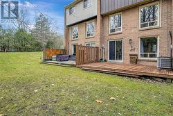 Rear view of property featuring a lawn, cooling unit, and a deck - 