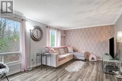 Living room featuring wood-type flooring, a textured ceiling, and ornamental molding - 