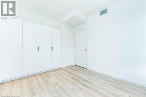 Primary bedroom, large wall-to-wall closet system, potlights and luxury laminate flooring - 741 King Street W Unit# 301, Kitchener, ON - Indoor Photo Showing Other Room