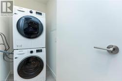 Clothes washing area featuring stacked washing maching and dryer and light tile patterned floors - 