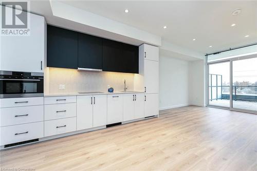 Kitchen with tasteful backsplash, stovetop, light luxury laminate flooring, white cabinets, integrated appliances and oven - 741 King Street W Unit# 301, Kitchener, ON - Indoor Photo Showing Kitchen With Upgraded Kitchen