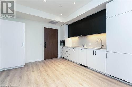 Kitchen featuring backsplash, white cabinets, oven, sink, and luxury laminate flooring - 741 King Street W Unit# 301, Kitchener, ON - Indoor Photo Showing Kitchen