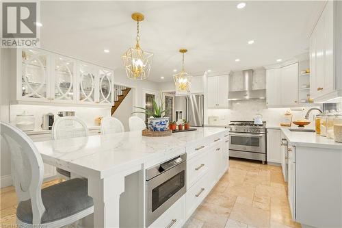 Kitchen featuring wall chimney exhaust hood, a kitchen island, high quality appliances, and white cabinetry - 659 Deervalley Road, Ancaster, ON - Indoor Photo Showing Kitchen With Stainless Steel Kitchen With Upgraded Kitchen