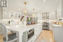 Kitchen featuring wall chimney exhaust hood, a kitchen island, high quality appliances, and white cabinetry - 