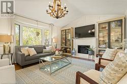 Living room featuring a premium fireplace, an inviting chandelier, lofted ceiling, and hardwood / wood-style flooring - 