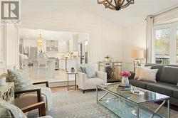 Living room with a chandelier, vaulted ceiling, and light wood-type flooring - 