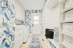 Laundry room with separate washer and dryer, light tile patterned floors, and cabinets - 