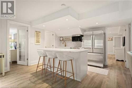 Kitchen featuring a breakfast bar, a kitchen island, light wood-type flooring, and appliances with stainless steel finishes - 659 Deervalley Road, Ancaster, ON - Indoor Photo Showing Kitchen With Upgraded Kitchen