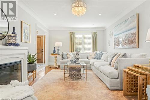 Living room featuring crown molding, a notable chandelier, and light wood-type flooring - 659 Deervalley Road, Ancaster, ON - Indoor Photo Showing Living Room With Fireplace