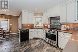 Kitchen featuring sink, black dishwasher, white cabinets, and stainless steel gas range - 