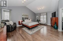 Bedroom with track lighting, vaulted ceiling, and hardwood / wood-style flooring - 