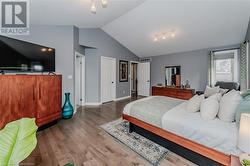 Bedroom featuring hardwood / wood-style flooring, track lighting, and vaulted ceiling - 