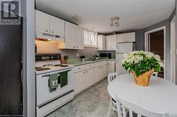 Kitchen with white appliances, white cabinetry, and sink - 