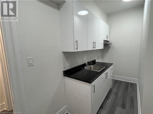 Kitchen featuring decorative backsplash, dark hardwood / wood-style flooring, white cabinetry, and sink - 660 Main Street E Unit# 1, Hamilton, ON - Indoor Photo Showing Kitchen