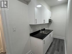 Kitchen featuring decorative backsplash, dark hardwood / wood-style flooring, white cabinetry, and sink - 