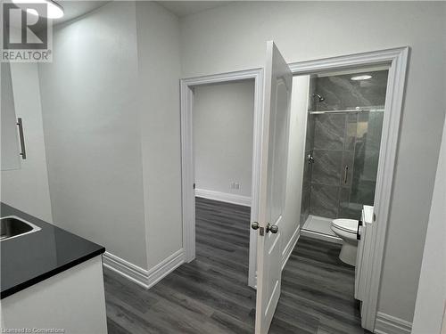 Bathroom featuring wood-type flooring, vanity, toilet, and an enclosed shower - 660 Main Street E Unit# 1, Hamilton, ON - Indoor Photo Showing Bathroom