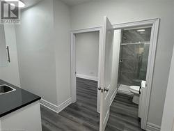 Bathroom featuring wood-type flooring, vanity, toilet, and an enclosed shower - 