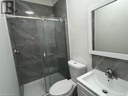 Bathroom featuring decorative backsplash, vanity, an enclosed shower, and toilet - 